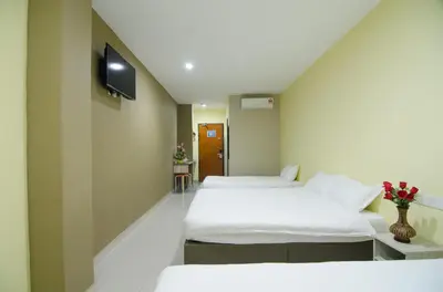 a room with three beds and a tv on the wall at Hotel Raja Bot in Kuala Lumpur