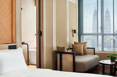 a bedroom with a bed and a chair and a window at The RuMa Hotel and Residences in Kuala Lumpur
