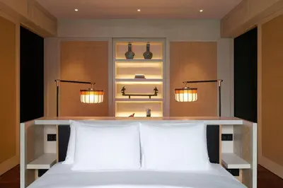 a bedroom with a bed with two pillows and two lights at The RuMa Hotel and Residences in Kuala Lumpur