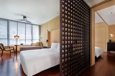 a bedroom with a white bed and a living room at The RuMa Hotel and Residences in Kuala Lumpur
