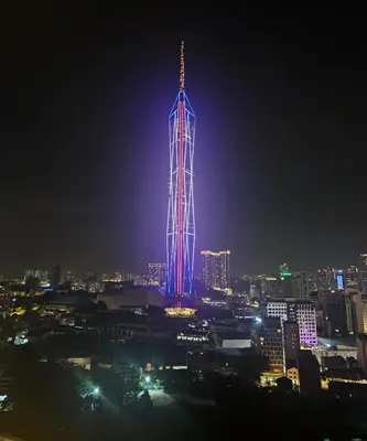 a tall building lit up in blue and purple at night at Holiday Paradise in Kuala Lumpur
