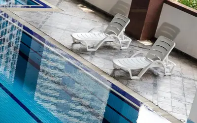 two white chairs sitting next to a swimming pool at The Maple Suite in Kuala Lumpur