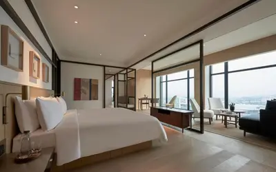 a bedroom with a large white bed and a living room at Alila Bangsar Kuala Lumpur in Kuala Lumpur