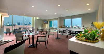 a restaurant with tables and chairs with a view of the city at Furama Bukit Bintang, Kuala Lumpur in Kuala Lumpur
