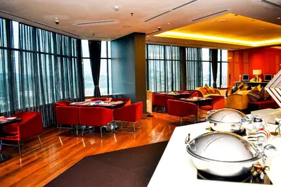 a restaurant with red chairs and tables and windows at Wyndham Grand Bangsar Kuala Lumpur in Kuala Lumpur