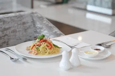 a plate of pasta with shrimp and vegetables on a table at Damas Suites & Residences Kuala Lumpur in Kuala Lumpur