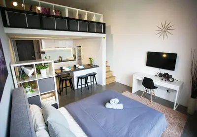 a living room with a blue bed and a kitchen at KL Sentral, EST Bangsar by SkyLimit Suites in Kuala Lumpur