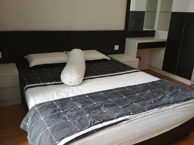 a bed with a black blanket and pillows on it at Soho Suites KLCC by Elite in Kuala Lumpur