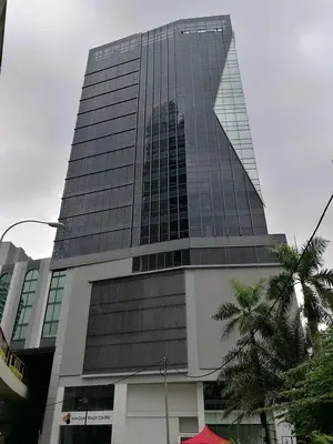a tall glass building with a palm tree in front of it at Imperial Regency Suites & Kuala Lumpur in Kuala Lumpur