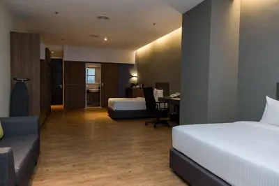 a hotel room with two beds and a desk at Imperial Regency Suites & Kuala Lumpur in Kuala Lumpur