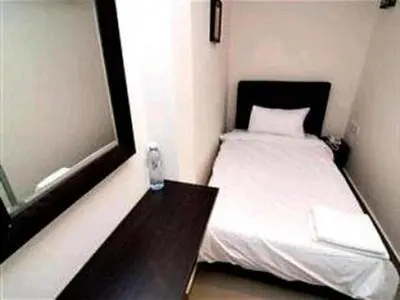 a small bedroom with a white bed and a table at Hotel A-One in Kuala Lumpur