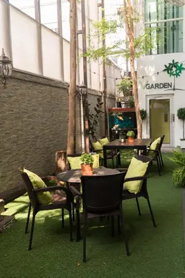 an outdoor patio with tables and chairs and trees at V Garden Hotel in Kuala Lumpur