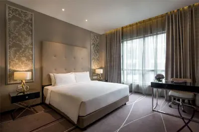 a bedroom with a bed and a desk and a window at Dorsett Hartamas Kuala Lumpur in Kuala Lumpur