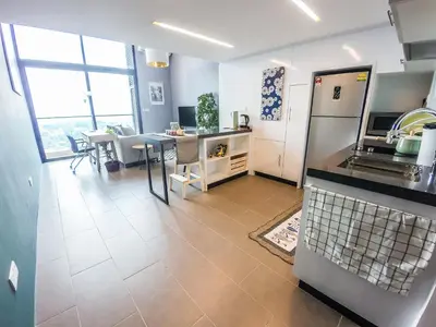 a kitchen and dining room with a table and a refrigerator at EST Suites Bangsar by Airhost in Kuala Lumpur