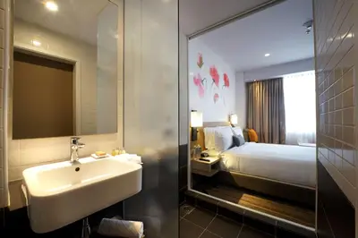 a bathroom with a sink and a bed and a mirror at Hilton Garden Inn Kuala Lumpur - South in Kuala Lumpur