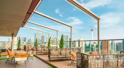 a balcony with chairs and tables and a view of the city at Hilton Garden Inn Kuala Lumpur - South in Kuala Lumpur