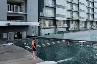 a woman standing in a swimming pool next to a building at One-Stop Residence & Hotel in Kuala Lumpur