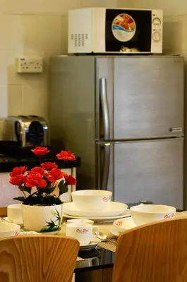 a kitchen with a table with plates and a refrigerator at One-Stop Residence & Hotel in Kuala Lumpur