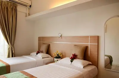 two beds in a hotel room with flowers at One-Stop Residence & Hotel in Kuala Lumpur