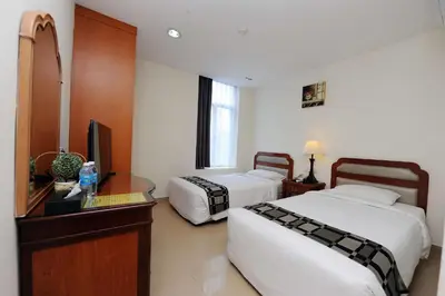 a hotel room with two beds and a desk and a television at Palm Inn Ampang Point in Ampang