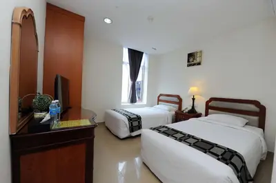 a bedroom with two beds and a desk and a television at Palm Inn Ampang Point in Ampang