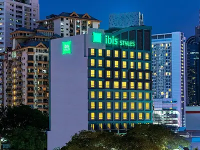 a tall building with two green signs on it at ibis Styles Kuala Lumpur Bukit Bintang in Kuala Lumpur