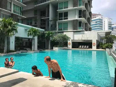 a man and two children in a swimming pool at Urban Suites @ Swiss Garden Residence in Kuala Lumpur