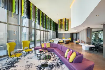 a living room with a purple couch and yellow chairs at W Kuala Lumpur in Kuala Lumpur