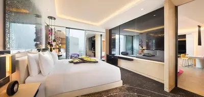 a bedroom with a large white bed and a living room at W Kuala Lumpur in Kuala Lumpur