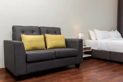 a gray chair with two yellow pillows next to a bed at Imperial Regency Suites & Petaling Jaya in Kuala Lumpur