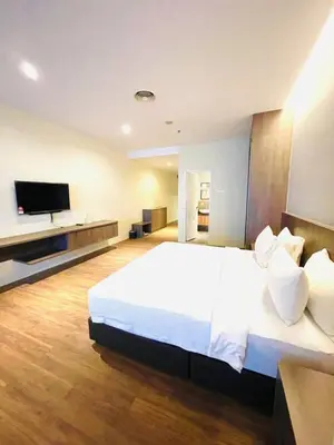 a bedroom with a large white bed and a flat screen tv at Imperial Regency Suites & Petaling Jaya in Kuala Lumpur