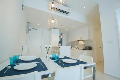 a white dining room with a table and white chairs at Robertson Suites Kuala Lumpur in Kuala Lumpur