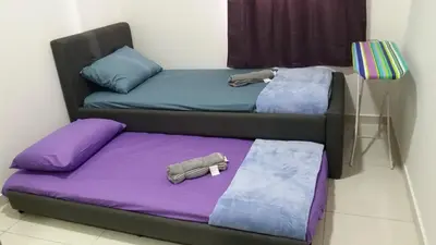 two beds in a room with purple and blue pillows at Adna Homestay Wangsa Maju in Kuala Lumpur