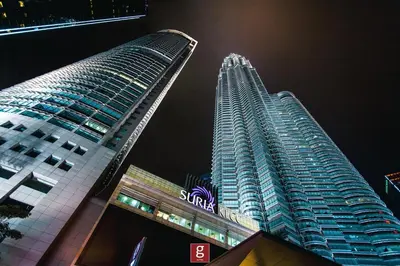 two tall buildings are next to each other at night at EXPRESSIONZ KLCC BY G Suites in Kuala Lumpur
