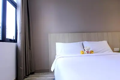 a white bed with a teddy bear sitting on it at Pacific Express Hotel Chinatown in Kuala Lumpur