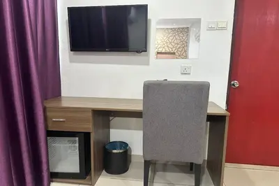 a desk with a chair and a television on a wall at Poorna Hotel at Jalan Ipoh Sentul Kuala Lumpur in Kuala Lumpur
