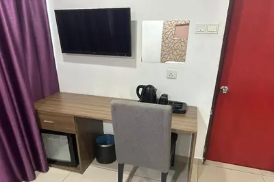 a desk with a chair and a television on a wall at Poorna Hotel at Jalan Ipoh Sentul Kuala Lumpur in Kuala Lumpur