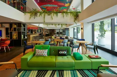 a green couch in a room with tables and chairs at citizenM Kuala Lumpur in Kuala Lumpur