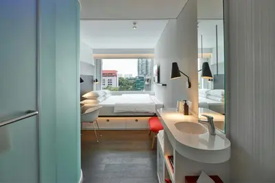 a bathroom with a sink and a bedroom with a bed at citizenM Kuala Lumpur in Kuala Lumpur