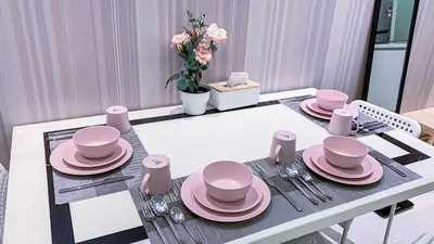 a dining room table with pink dishes on it at Soho Suites KLCC by Alucard\uff08\u5409\u9686\u5761KLCC Alucard Soho\u5957\u623f\u516c\u5bd3\uff09 in Kuala Lumpur