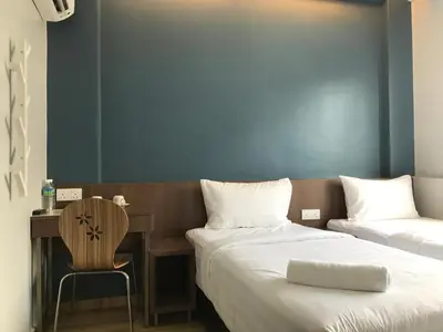 a bedroom with two beds and a desk and a chair at Festival Boutique Hotel - Damai Complex in Kuala Lumpur
