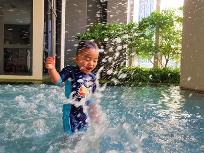 a young boy playing in a water fountain at The Mews KLCC by Plush in Kuala Lumpur