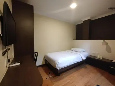 a bedroom with a bed and a desk and a tv at Hotel De Grand Orchard in Kuala Lumpur
