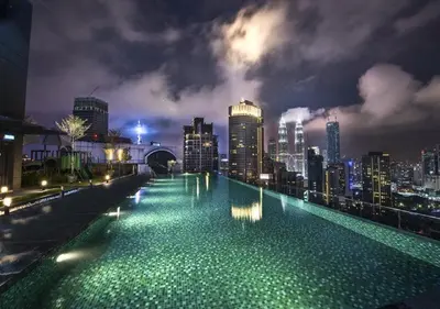 a large swimming pool with a city skyline at night at Maxhome@Dorsett Residence , KL in Kuala Lumpur
