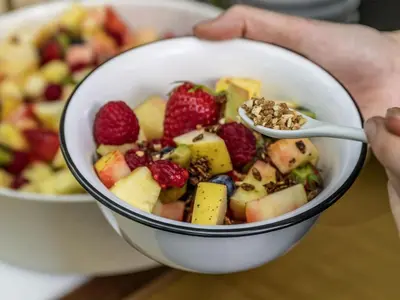 a person holding a bowl of fruit with a spoon at Ibis Styles Kuala Lumpur Fraser Business Park in Kuala Lumpur
