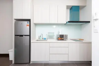 a kitchen with white cabinets and a refrigerator at Velocity KL By PSM Luxury Suites in Kuala Lumpur