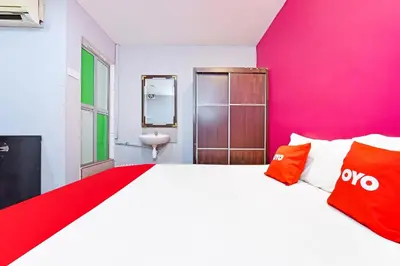 a bedroom with a large bed and a pink wall at Hotel O Elwarda Klcity in Kuala Lumpur