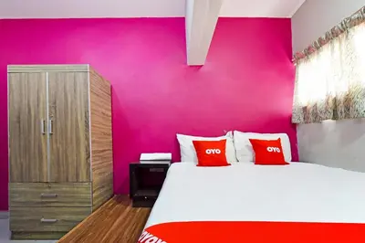 a bedroom with a pink wall and a bed with red pillows at Hotel O Elwarda Klcity in Kuala Lumpur