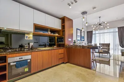 a kitchen with wooden cabinets and a dining room at Anggun Residences Serviced Suites in Kuala Lumpur