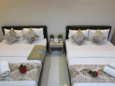 two twin beds in a room with a table at Safari Hotel in Kuala Lumpur